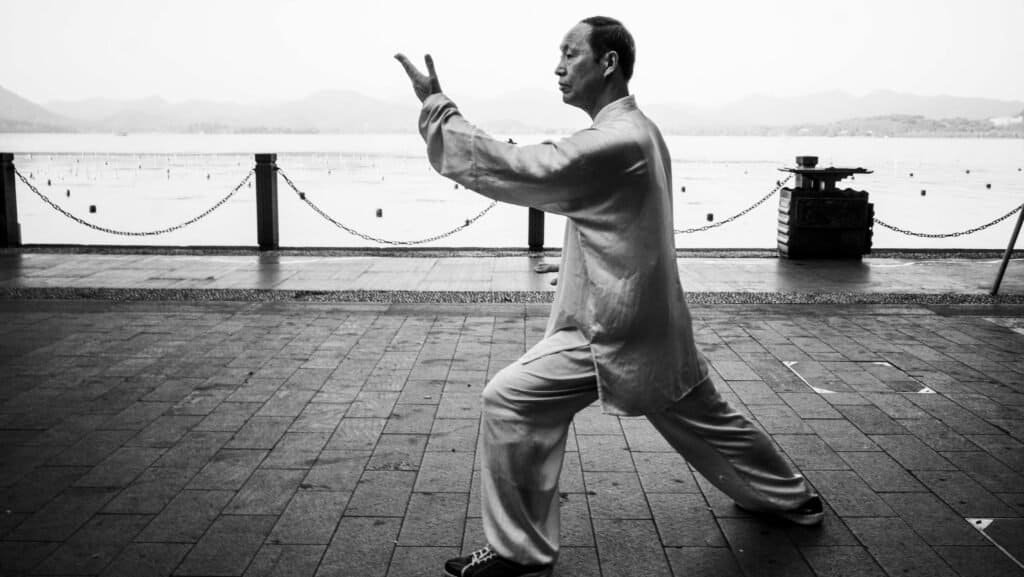 Man practices taichi, by the side of west lake in Hangzhou, china. In the morning, black and white.