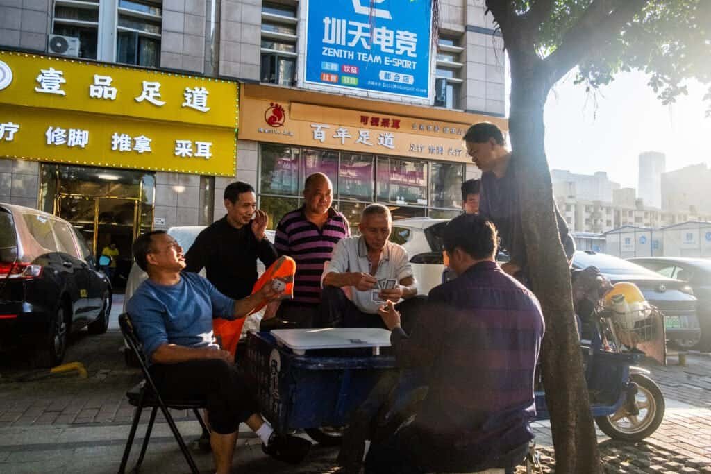 Men street, cards, street, chairs bikes, table, tree, shops