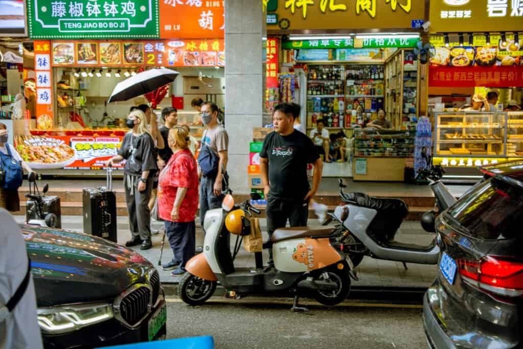 In dongmen Shenzhen china taken on Cannon 6d Mark man with ebike on crowded street daytime