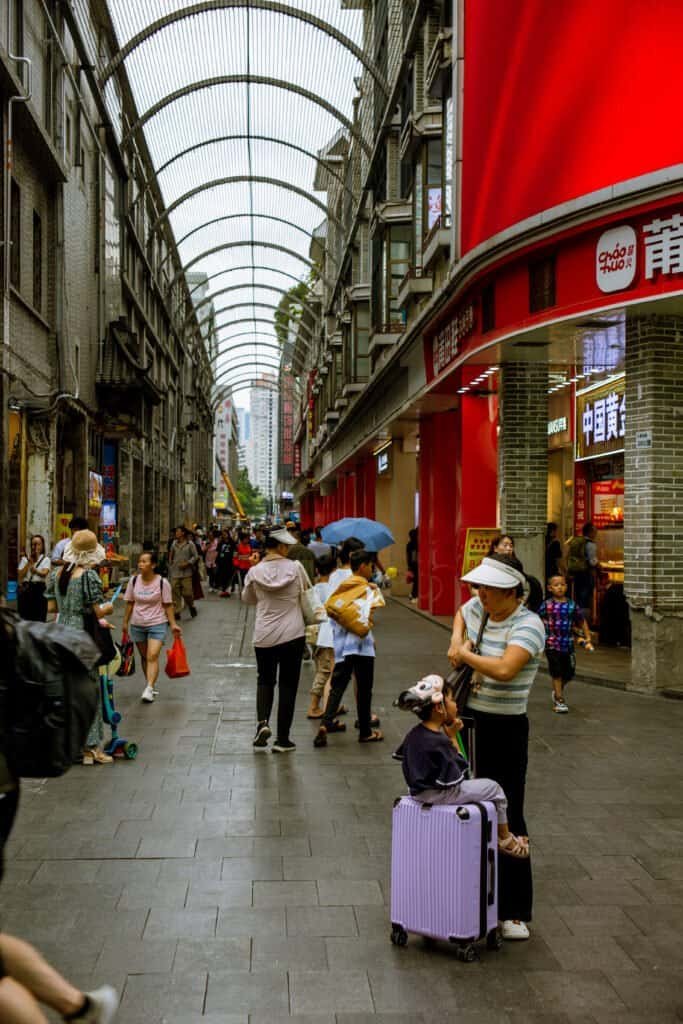 In dongmen Shenzhen china taken on Cannon 6d Mark 1 man sits on shops beautiful roof and signs all around daytime street