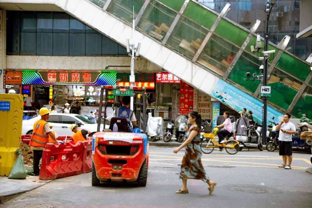 In dongmen Shenzhen china taken on Cannon 6d Mark builders pedestrians woman walks across street on crowded street daytime