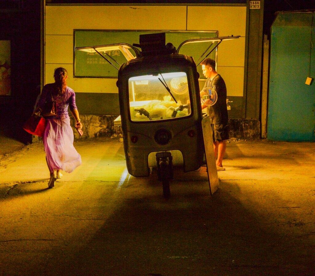 BBQ vendor nanshan shekou port Shenzhen china Night lady walks by man cooks noodles night shot Nikon d600
