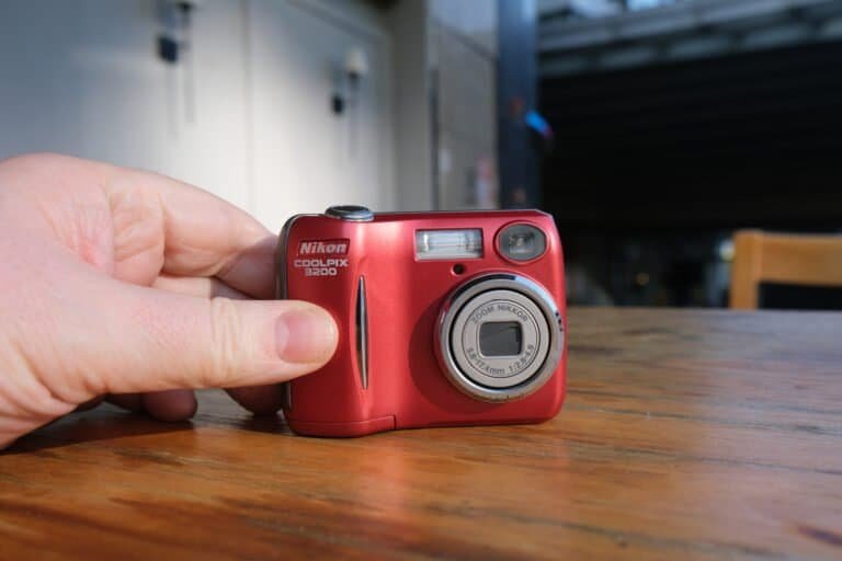 Nikon Coolpix 3200 front on Wooden table hands sunshine chair