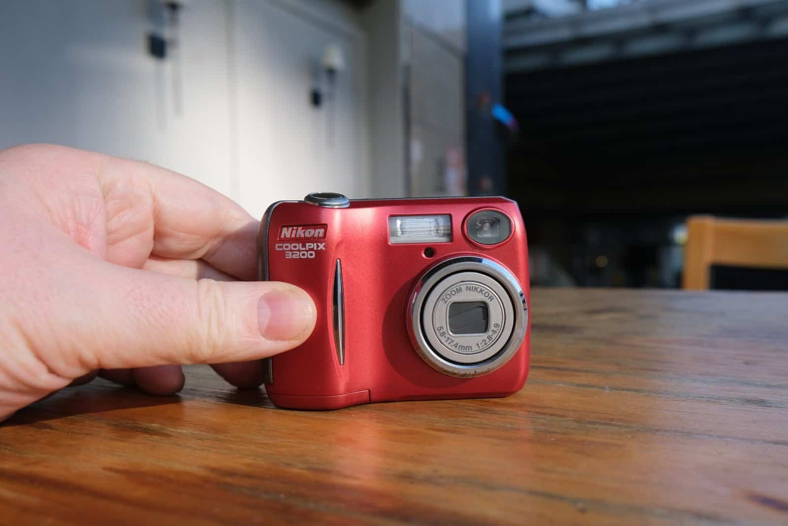 Nikon Coolpix 3200 front on Wooden table hands sunshine chair