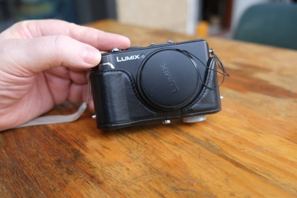 Panasonic LUMiX DMC LX3 in leather case hand table Half on half off lens cap