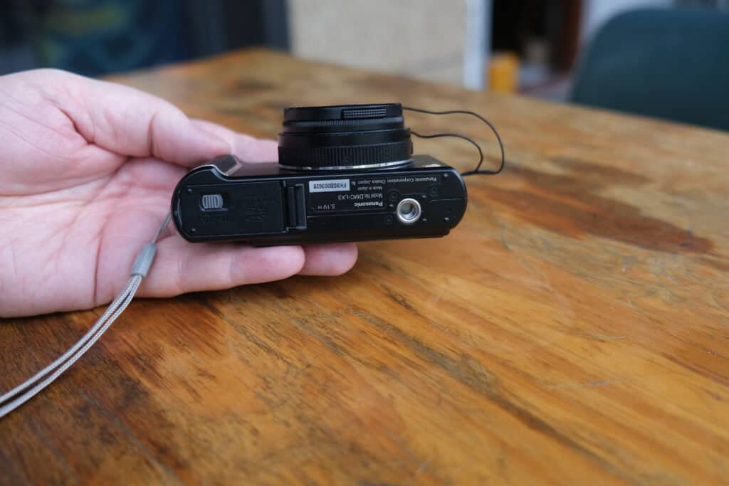 Panasonic LUMiX DMC LX3 in leather case hand table lens cap strap bottom view