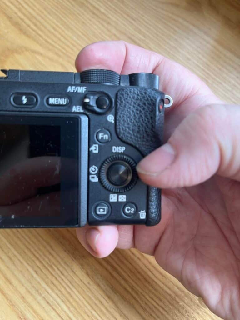 Hand holding a digital camera with a textured grip ready to capture a photo directional dial Sony a6300