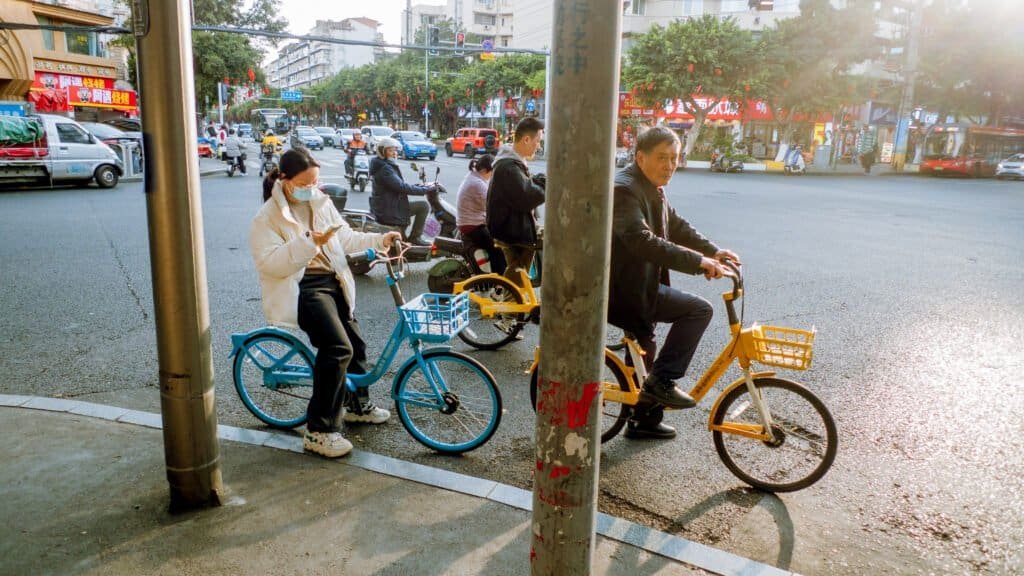 People on bikes at cross road in Chengdu china afternoon light man woman yellow bike blue bike