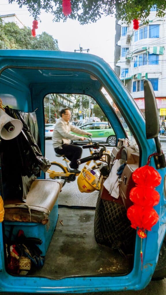 Man on bike in car Chengdu china street car road workers cleaners vehicle day time man lanterns